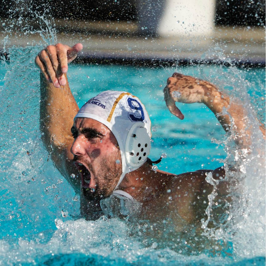 California B.U. Water Polo Hombre de waterpolo gritando y chapoteando en el agua durante un partido.